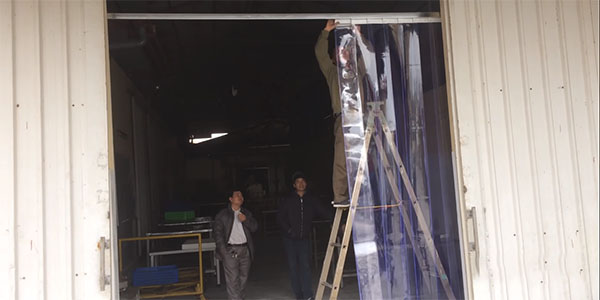 Nhân công đang lắp đặt rèm cho kho xưởng